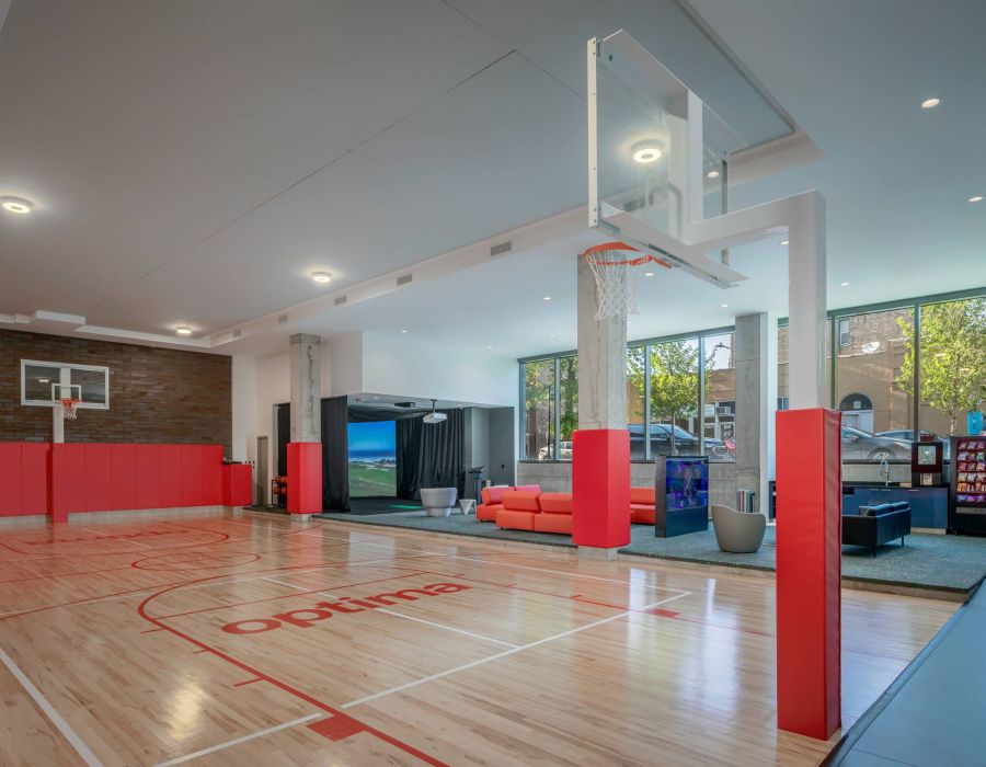 Optima Lakeview® Apartments in Chicago, IL Indoor basketball court with red and white markings, red seating area, and large windows letting in natural light.