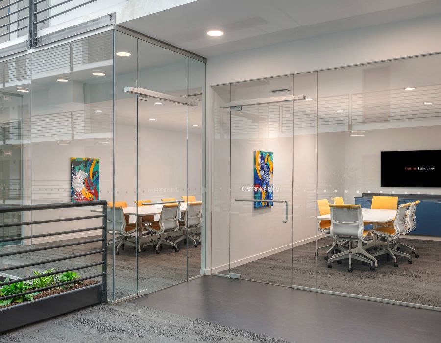 Optima Lakeview® Apartments in Chicago, IL Modern glass-walled conference rooms with tables, chairs, colorful art, and a wall-mounted screen.